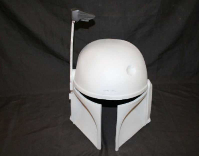 May include: A white Mandalorian helmet with a distinctive T-shaped visor and a rangefinder extending from the right side. The helmet has a rounded top and angled cheek plates, with a dark interior visible at the visor opening. A classic Star Wars costume accessory.