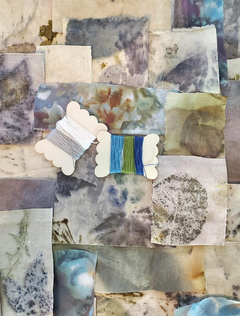 May include: A collection of fabric swatches in various shades of blue, green, brown, and white, with a few pieces of embroidery floss on wooden spools.