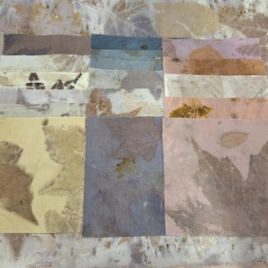 May include: A collection of square fabric swatches featuring botanical leaf prints in various earth tones including yellow, blue, pink, and brown. Each piece displays unique natural foliage patterns transferred onto the textile surface.