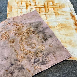 May include: Two pieces of fabric dyed with rust. One piece is a light pink with a brown circular pattern. The other piece is a white fabric with a brown grid pattern.