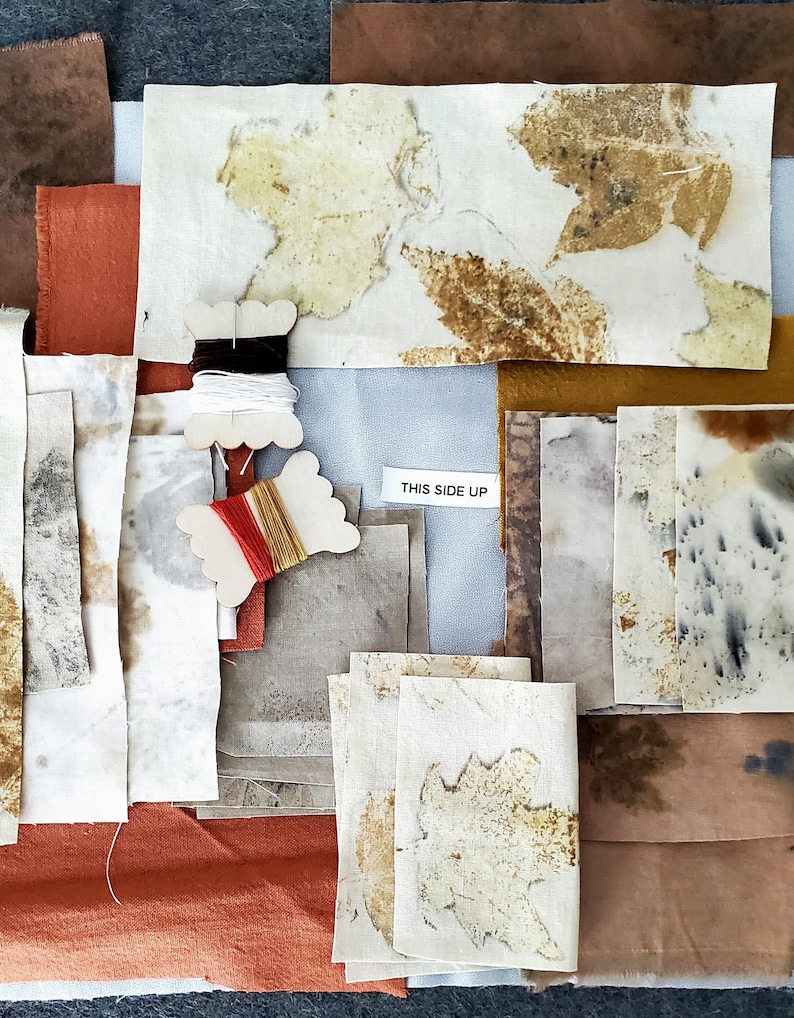 May include: A collection of fabric squares with various shades of brown, beige, and orange. Some squares have leaf patterns, while others have a speckled or mottled appearance. The fabric squares are arranged on a gray surface. The text "THIS SIDE UP" is visible on a white label.