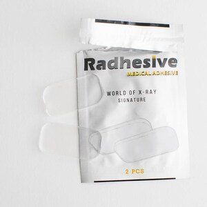May include: A package of two clear medical adhesive pads labeled "Radhesive Medical Adhesive" and "World of X-Ray Signature". The package also says "2 PCS".