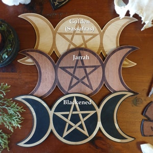 May include: Three wooden triple moon pentacles, one in golden (Sassafras) wood, one in Jarrah wood, and one in blackened wood.