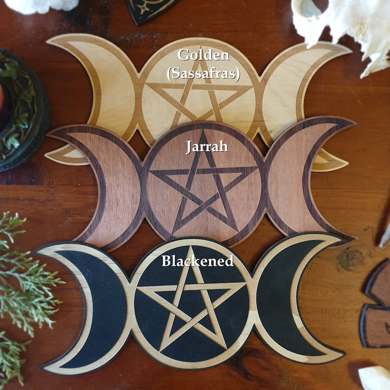May include: Three wooden triple moon pentacles, one in golden (Sassafras) wood, one in Jarrah wood, and one in blackened wood.