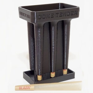 May include: A black "Cone Tender" with four cone-shaped holders and a base. The text "SIZE 1 1/4" and "CONE TENDER" are visible on the top. A pre-rolled cone with "RAW" text is in front of the holder.