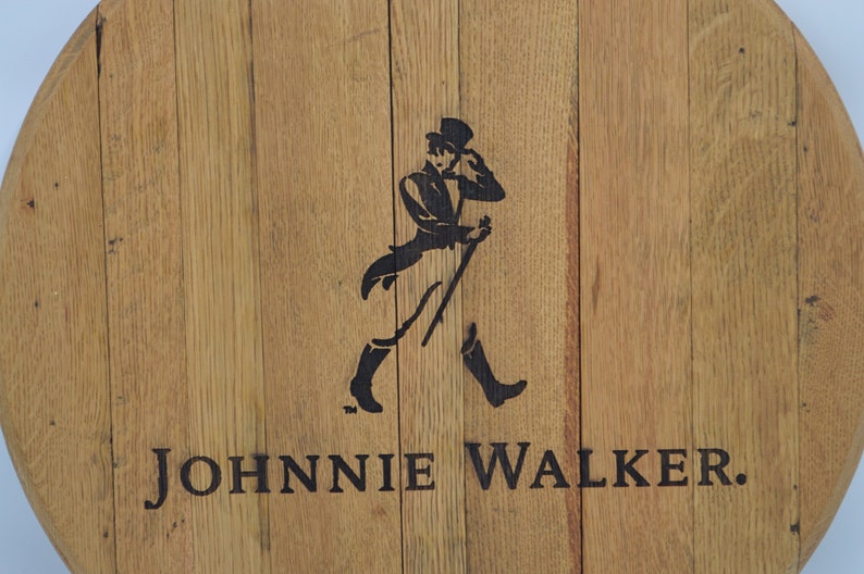 May include: A round wooden sign with the Johnnie Walker logo. The logo features a man in a top hat and walking stick, with the text "JOHNNIE WALKER." printed below.