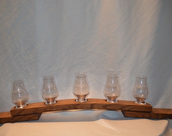 May include: A wooden whiskey tasting tray with five clear glass whiskey glasses. The tray is made from reclaimed oak barrel staves.