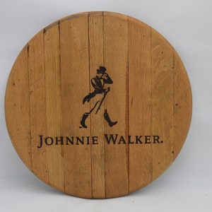 May include: A round wooden sign with the Johnnie Walker logo. The logo features a man in a top hat and walking stick, with the text "JOHNNIE WALKER." below.
