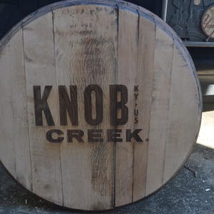 May include: A wooden barrel head with the words "Knob Creek KY, US" and "Knob Creek" burned into the surface.