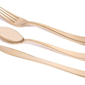 May include: A set of three gold-colored plastic utensils: a fork, a spoon, and a knife. The utensils are arranged in a row on a white background.