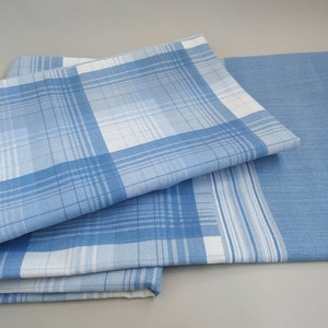 May include: A set of three blue and white plaid fabric napkins. The napkins are folded and stacked on top of each other.