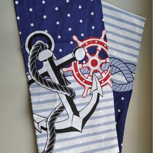 May include: A blue and white fabric with a black anchor and red and white steering wheel design. The fabric has a white background with blue stripes and white polka dots.