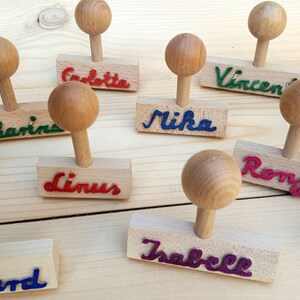 K&ouml;nnte beinhalten: Ein Set mit 10 Holzstempeln mit verschiedenen Namen, die in bunter Tinte geschrieben sind. Die Stempel sind aus Naturholz gefertigt und haben einen runden Griff. Die Namen auf den Stempeln sind: Lukas, Catharina, Linus, Mika, Vincent, Ronja, Kai, Isabelle, Chiara und Lennard.
