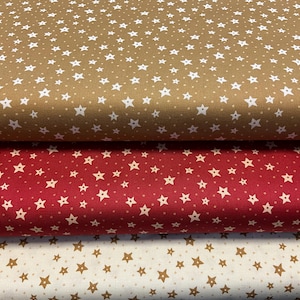 以下が含まれることがあります： 星柄の生地が3ロール。一番上のロールはタン色に白い星、真ん中のロールは赤に白い星、一番下のロールはオフホワイトにタン色の星です。生地はおそらく綿です。