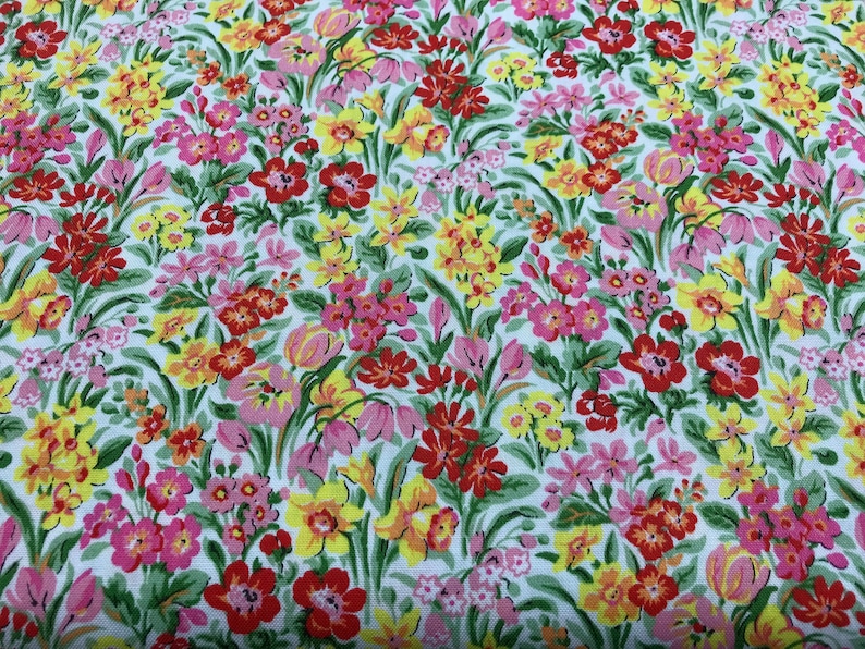 May include: A white fabric with a floral print featuring red, yellow, and pink flowers. The fabric is covered in a variety of flowers, creating a busy and colorful pattern.