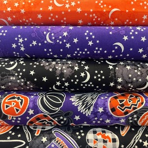 May include: A stack of Halloween-themed fabric rolls. The top roll is orange with white stars and crescent moons. Below are purple, black, and patterned fabrics with pumpkins, witch hats, and stars. The fabrics are suitable for crafting.