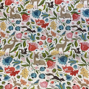 May include: White fabric with a repeating pattern of woodland creatures and floral elements. The design includes deer, foxes, squirrels, rabbits, and birds, along with flowers and leaves in shades of red, blue, pink, and yellow.