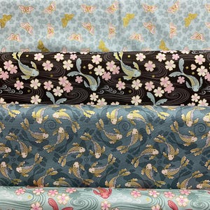 以下が含まれることがあります： さまざまな模様の生地ロールのコレクション。模様には、蝶、鯉、桜が様々な色で描かれています。生地は、縫製や手芸プロジェクトに適した、繰り返しのモチーフを持つ濃淡の背景が特徴です。
