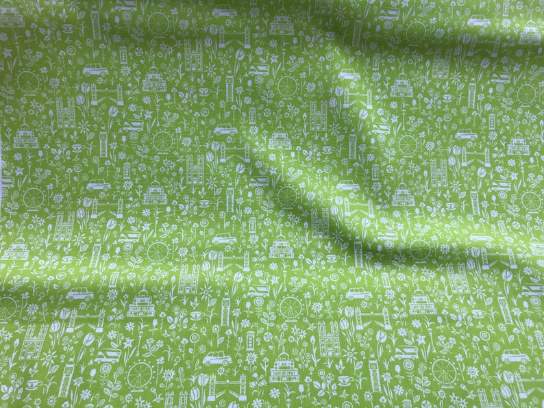 May include: Green fabric with a white repeating pattern of London landmarks, including Big Ben, the London Eye, double-decker buses, and red telephone booths.