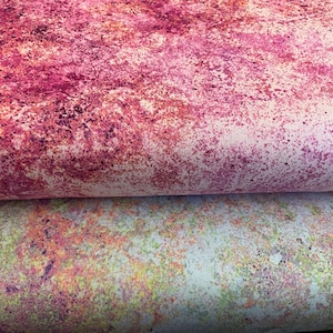 May include: Close-up of two fabric samples with abstract designs. The top fabric features a blend of pink and burgundy hues with a speckled pattern. The bottom fabric has a mix of green, yellow, and orange speckles on a white background.