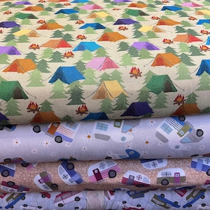 Może przedstawiać: Stos tkanin z motywami kempingowymi. Górna tkanina ma powtarzający się wzór kolorowych namiotów, ognisk i zielonych drzew na beżowym tle. Poniżej tkaniny ze wzorami kamperów i stokrotek.