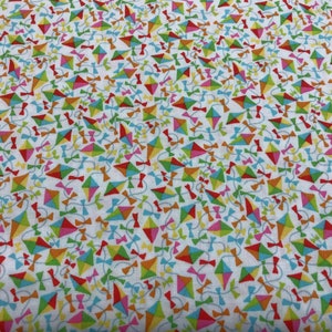 May include: White fabric with a repeating pattern of colorful kites with strings and bows. The kites are in various shades of red, orange, yellow, green, blue, and pink.