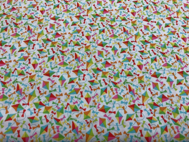 May include: White fabric with a repeating pattern of colorful kites with strings and bows. The kites are in various shades of red, orange, yellow, green, blue, and pink.