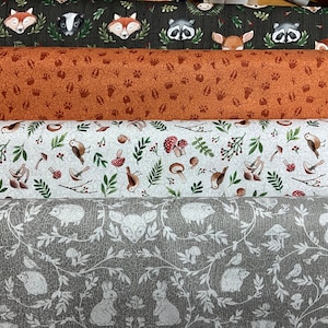 Könnte beinhalten: Vier verschiedene Stoffmuster mit Waldtier- und Naturdrucken. Das oberste Muster zeigt einen dunkelgrünen Hintergrund mit braunen, weißen und roten Tierdrucken. Das zweite Muster ist rostorange mit braunen Pfotenabdrücken. Das dritte Muster ist weiß mit grünen Blättern, braunen Pilzen und roten Beeren. Das unterste Muster ist hellgrau mit weißen Ranken, Blättern und Tieren.