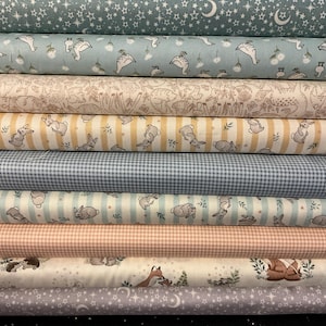 May include: A selection of rolled fabrics with diverse patterns. Designs feature bunnies, stars, moons, and gingham. The colour palette includes light blue, yellow, pink, and grey. The image displays the variety of patterns and textures available.