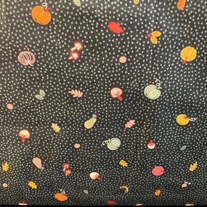 May include: Dark fabric featuring a repeating pattern of pumpkins, mushrooms, and leaves in orange, yellow, and pink. The design is set against a black background with small white dots, creating an autumnal theme.