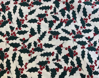 May include: A white fabric with a repeating pattern of green holly leaves and red berries.