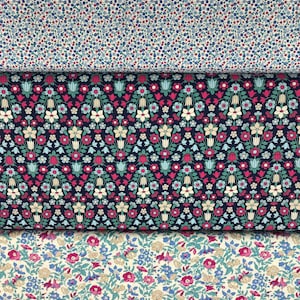May include: Three fabric swatches featuring different floral designs. The top swatch has a white background with tiny blue, pink, and green flowers. The middle swatch has a dark blue background with a repeating pattern of pink, white, and blue flowers. The bottom swatch has a cream background with small pink, blue, and green flowers.