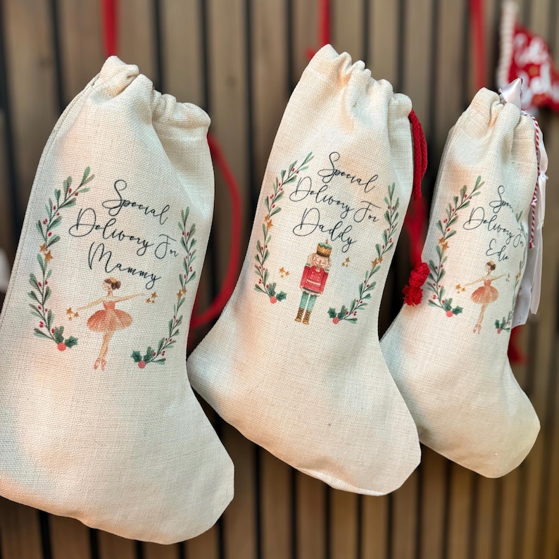 Pode incluir: Tr&ecirc;s meias de Natal personalizadas feitas de juta bege com cord&otilde;es de ajuste vermelhos. As meias s&atilde;o decoradas com uma coroa verde e um design festivo. As meias s&atilde;o etiquetadas como "Entrega especial para mam&atilde;e", "Entrega especial para papai" e "Entrega especial para Ellie".