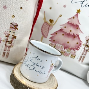 May include: White enamel mug with a pink ballerina and gold stars. The mug says "Edie's Christmas Hot Chocolate".