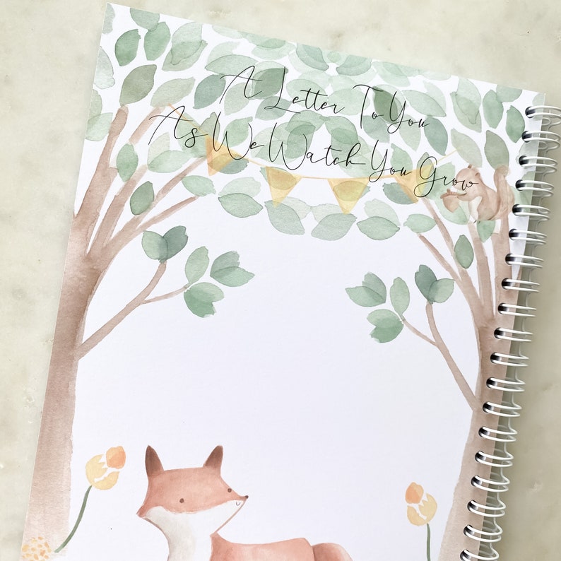 K&ouml;nnte beinhalten: Eine Aquarell-Illustration einer Waldszene mit einem Fuchs und einem Eichh&ouml;rnchen. Der Text "A Letter To You As We Watch You Grow" steht auf der Seite. Dies ist ein leeres Tagebuch mit einer Spiralbindung.