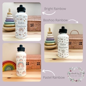 May include: Three personalized water bottles with different rainbow designs. The bottles are white with a black lid and a black handle. The designs are "Bright Rainbow", "Boohoo Rainbow", and "Pastel Rainbow".