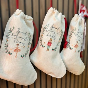 Pode incluir: Tr&ecirc;s meias de Natal personalizadas feitas de tecido de juta natural. As meias apresentam um design festivo de grinalda verde com uma bailarina, um quebra-nozes e o texto "Entrega especial para mam&atilde;e", "Entrega especial para papai" e "Entrega especial para Ellie".