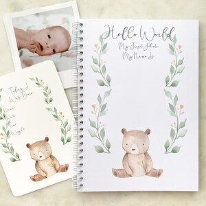 K&ouml;nnte beinhalten: Ein wei&szlig;es Babybuch mit einer Illustration eines braunen B&auml;ren und dem Text "Hello World, My First Photo, My Name Is". Das Buch hat eine Spiralbindung und ein gr&uuml;nes und orangefarbenes Blumenmuster.