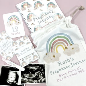 May include: A pregnancy journal with a rainbow and star design, a white canvas bag with a rainbow and star design, and a set of cards with rainbow and star designs. The bag and cards have the text "Pregnancy Journey" and "Making Memories". The journal has the text "Pregnancy Journey Memories & Moments".
