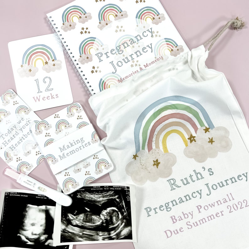 May include: A pregnancy journal with a rainbow and star design, a white canvas bag with a rainbow and star design, and a set of cards with rainbow and star designs. The bag and cards have the text "Pregnancy Journey" and "Making Memories". The journal has the text "Pregnancy Journey Memories & Moments".