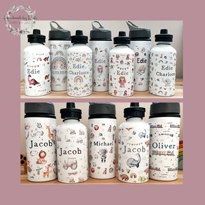 May include: A set of ten personalized water bottles with various colorful designs. The bottles are white with black lids and feature different patterns, including rainbows, dinosaurs, mermaids, and spaceships. The names "Edie", "Jacob", "Michael", "Oliver", and "Charlotte" are printed on the bottles.