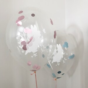 May include: Two clear balloons with white bunny silhouettes and confetti inside. The larger balloon has pink confetti and the smaller balloon has blue confetti.