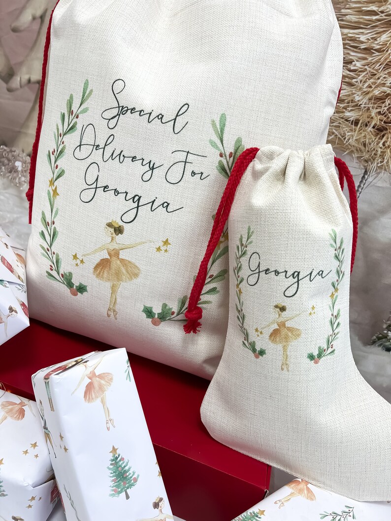 May include: A white canvas Christmas stocking with a red drawstring and a ballerina illustration. The stocking is personalized with the name "Georgia" and the text "Special Delivery For Georgia".