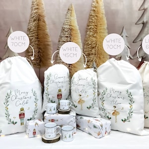 May include: Four white and one linen Christmas gift bags with personalized designs. The bags are decorated with a nutcracker, a ballerina, and greenery. The bags are available in sizes 70 cm, 45 cm, and 67 cm.