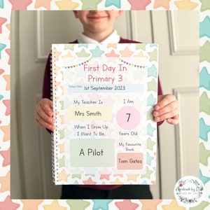 May include: A colorful notebook with a star pattern and the text "First Day In Primary 3" and "1st September 2023". The notebook has sections for the student to fill in their teacher's name, age, favorite book, and what they want to be when they grow up.