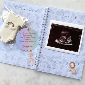 May include: A blue and white baby announcement scrapbook with a quote about dreams coming true, a cookie shaped like a onesie, and a first ultrasound image.