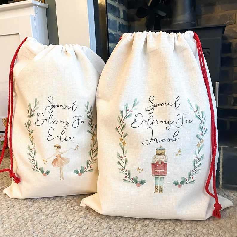 May include: Two personalized Christmas gift bags with red drawstrings. One bag features a ballerina and the text "Special Delivery For Edie". The other bag features a nutcracker and the text "Special Delivery For Jacob".