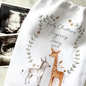May include: A white fabric bag with a green leafy border and gold stars. The text "Baby Chabbings Pregnancy Journey 2020/21" is printed in black cursive font. A watercolor illustration of a giraffe and zebra is in the center of the bag.