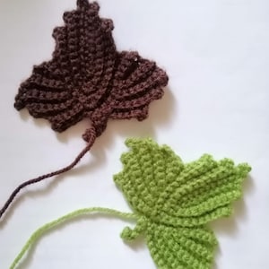 May include: Two crocheted leaves, one brown and one green, with long yarn tails attached.