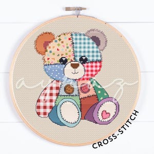 May include: A colorful patchwork teddy bear cross stitch pattern. The bear is made up of different colored squares and has a heart on its foot.